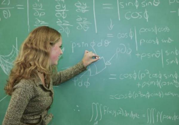 Young woman writing something on a blackboard