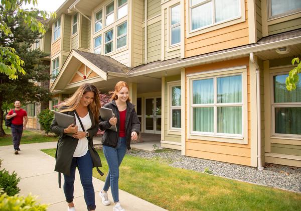 Happy students walking in front of student housing