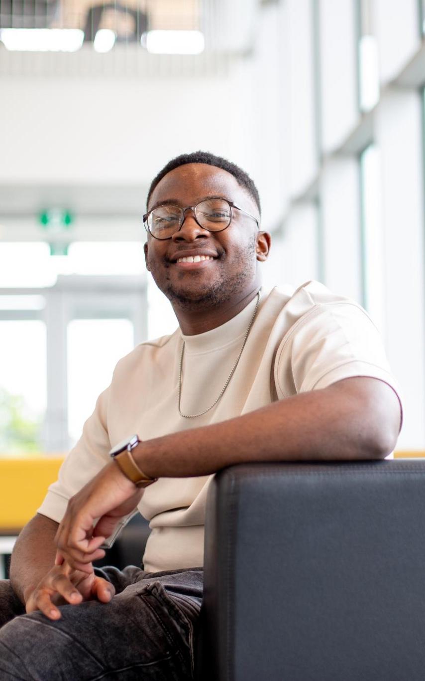 A smiling young man in a brightly lit room.